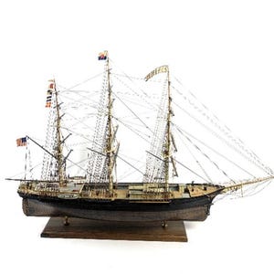 Peut inclure: Maquette détaillée d'un grand voilier avec plusieurs mâts, gréements et drapeaux. Le navire a une coque noire et une base en bois. Le modèle comprend des drapeaux américains et d'autres drapeaux de signalisation colorés. C'est une réplique détaillée.