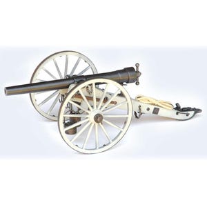 May include: A miniature cannon with a dark barrel and white wheels. The cannon is mounted on a white carriage with a rope coiled on the side. The wheels have multiple spokes.
