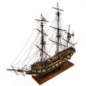 May include: A detailed wooden model of a tall ship, featuring multiple masts with intricate rigging and sails. The ship has a brown hull with yellow accents and is mounted on a wooden base. An American flag is visible.