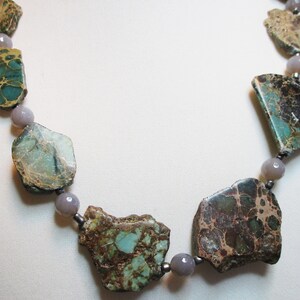 May include: A necklace made with large, irregular, green and brown jasper stones and smaller, round, gray stones.