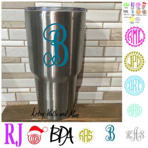 May include: A stainless steel tumbler with a teal monogram "B" on the side. The tumbler is sitting on a wood surface. The image also shows various monogram designs in different colors and styles.