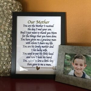 May include: A framed print with a poem about a mother, with the text "Our Mother You are the Mother I received the day I wed your son. And I just want to thank you Mom for the things that you have done. You have given me a gracious man with whom I share my life. You are his lovely mother and I his lucky wife. You used to pat his little head and now I hold his hand. You raised in love a little boy then gave to me a man."