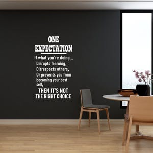 May include: A black wall with a white vinyl decal that reads "ONE EXPECTATION. If what you're doing... Disrupts learning, Disrespects others, Or prevents you from becoming your best self, THEN IT'S NOT THE RIGHT CHOICE."