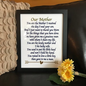 May include: A framed print with a poem about a mother. The poem is written in blue ink on a white background. The frame is black and the poem is titled "Our Mother".