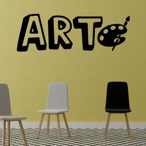 May include: A black and white wall decal with the word "ART" in a playful font and a paint palette with a paintbrush. Three chairs are in the foreground, two white and one black, with wooden legs. The chairs are on a black and white checkered floor.