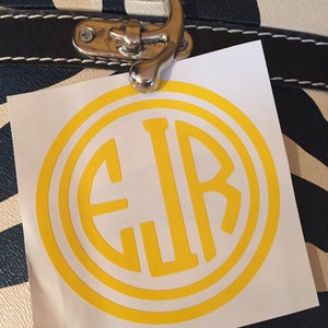 May include: A white sticker with a yellow circle containing the letters EJR in a monogram style.