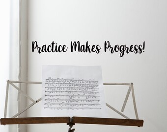 May include: A music stand holds sheet music against a white wall. The sheet music is in black and white. The words "Practice Makes Progress!" are written in black script above the music stand. The stand is made of metal and wood.
