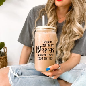 May include: A clear glass tumbler with a bamboo lid and a straw. The tumbler has a black graphic that reads "I will keep counting my blessings knowing I can't count that high."