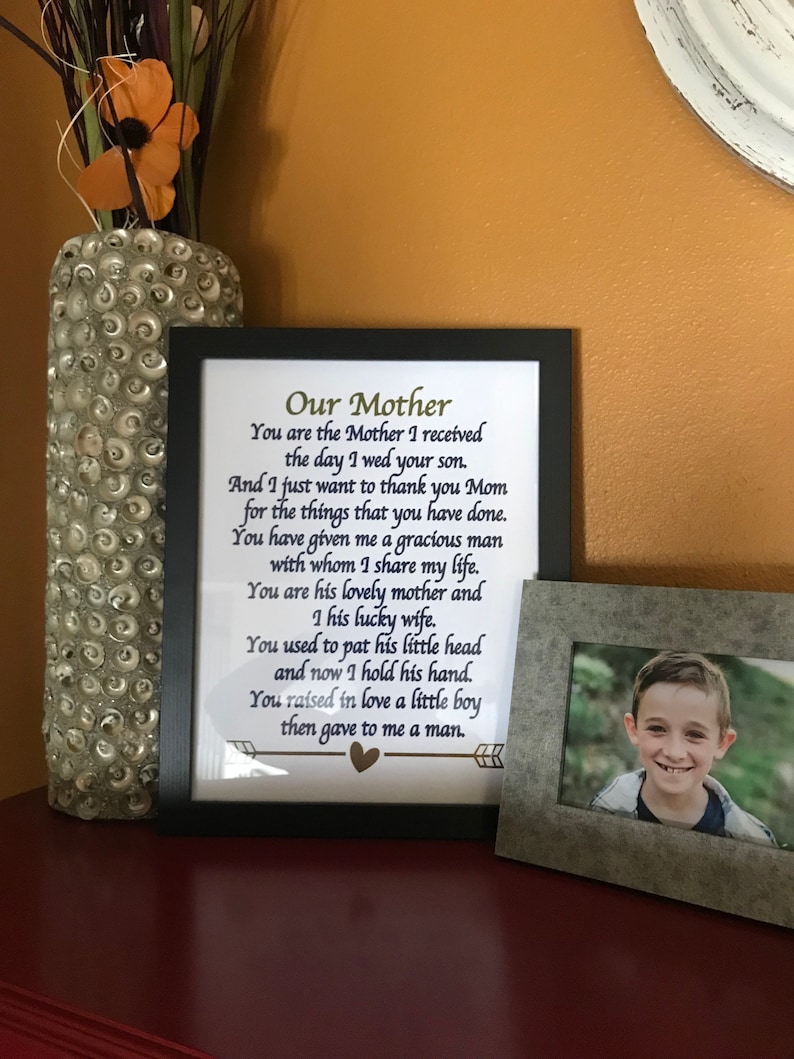 May include: A framed print with a poem about a mother, with the text "Our Mother You are the Mother I received the day I wed your son. And I just want to thank you Mom for the things that you have done. You have given me a gracious man with whom I share my life. You are his lovely mother and I his lucky wife. You used to pat his little head and now I hold his hand. You raised in love a little boy then gave to me a man."