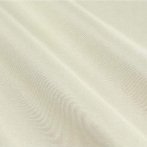 Op de afbeelding: Een effen gebroken witte stof met een zichtbare geweven textuur. Het materiaal vertoont diagonale plooien die zachte schaduwen en highlights over het oppervlak cre&euml;ren, wat het consistente weefpatroon en de neutrale, lichte cr&egrave;mekleur benadrukt.