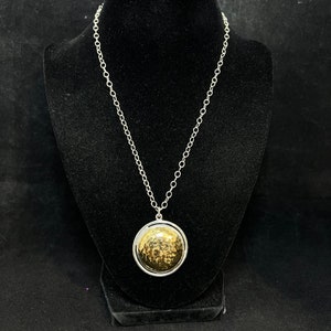 Può includere: Una collana a catena d'argento con un ciondolo rotondo in oro martellato.