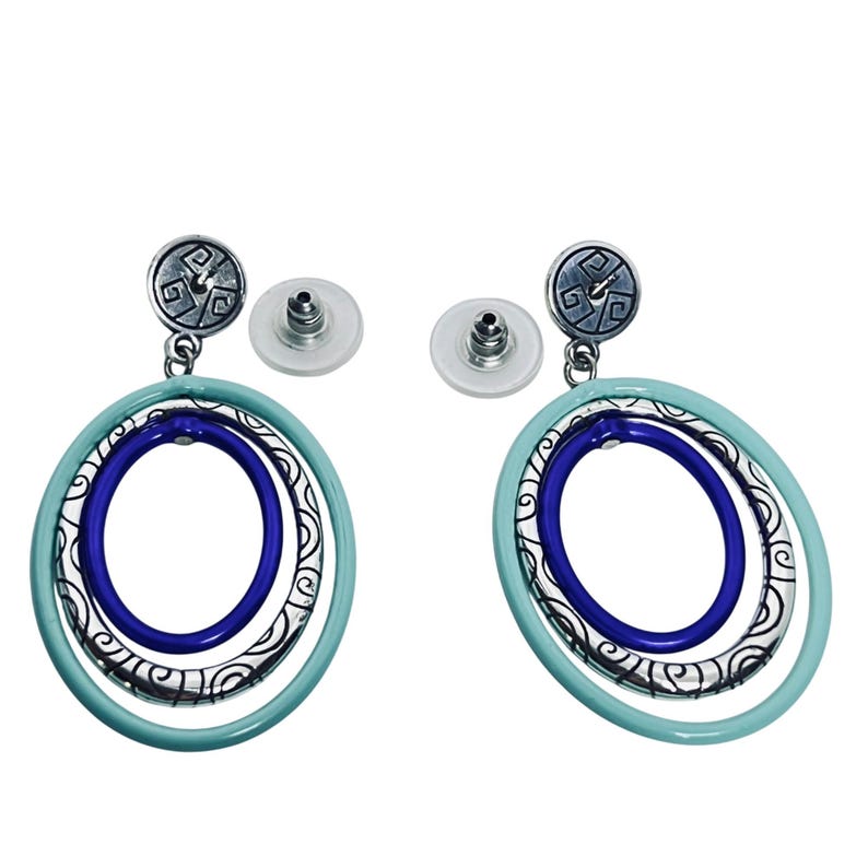 Puede incluir: Un par de pendientes colgantes con un &oacute;valo exterior azul claro, un &oacute;valo central de filigrana plateada y un &oacute;valo interior azul oscuro. Los pendientes tienen un perno plateado con un dise&ntilde;o decorativo y un respaldo transparente.