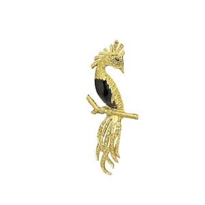 May include: A gold-toned bird brooch with a black body and a detailed tail, perched on a branch. The bird's head and tail feathers are adorned with small, sparkling accents. The brooch is designed with intricate details.
