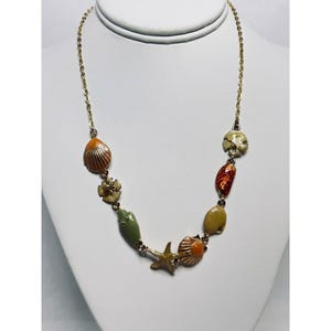 May include: A gold chain necklace with colorful enamel charms shaped like seashells, starfish, and sand dollars.