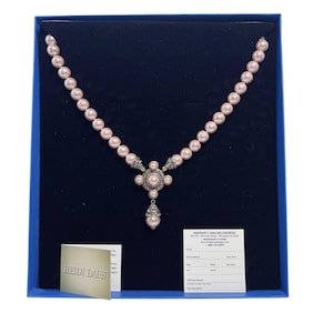 Könnte beinhalten: Eine rosa Perlenkette mit dekorativem Anhänger, präsentiert in einer blauen Box. Die Halskette hat einen zentralen Anhänger mit einer großen rosa Perle, umgeben von kleineren Perlen und klaren Akzenten. Eine Garantiekarte ist ebenfalls enthalten.