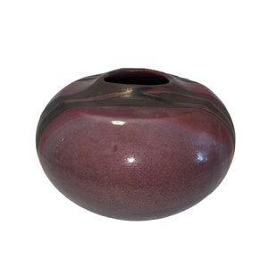 Könnte beinhalten: Eine runde, violette Keramikvase mit schwarzen und braunen Streifen. Die Vase hat eine glänzende Oberfläche.