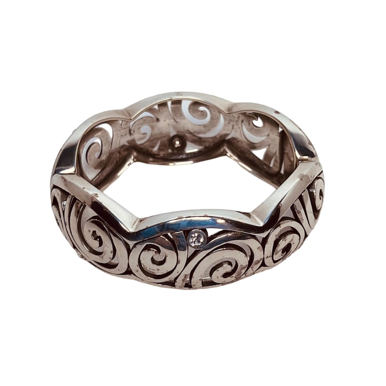 以下が含まれることがあります： 渦巻き模様と小さな透明な石が付いた銀の指輪