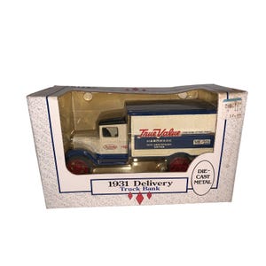 May include: A die-cast metal 1931 Delivery Truck Bank in its original packaging. The truck is white and blue with red wheels and features the "True Value Hardware" logo. The packaging includes the text "10th Anniversary Edition".