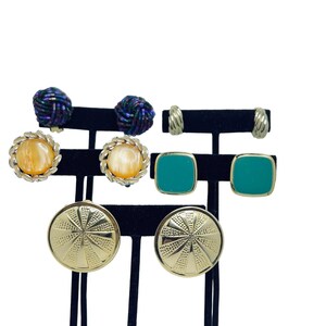 May include: Set of six vintage clip-on earrings. Two pairs are gold with a textured design, one pair is gold with a round orange stone, and one pair is square with a teal green stone.