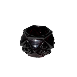 May include: A small, dark red glass bowl with a geometric design. The bowl has a hexagonal shape and is decorated with a pattern of raised dots.