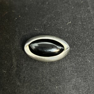 Peut inclure: Une bague ovale en argent avec une pierre précieuse noire au centre.