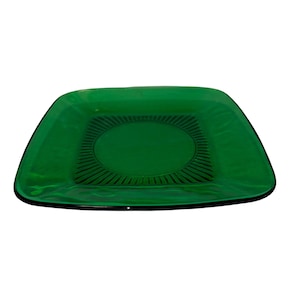Può includere: Un piatto da portata quadrato in vetro verde con un motivo decorativo a cerchio concentrico al centro.