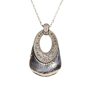May include: Silver necklace with a hammered-metal pendant. The pendant has an oval top section set with small, clear crystals. The lower part of the pendant has a textured, hammered finish.