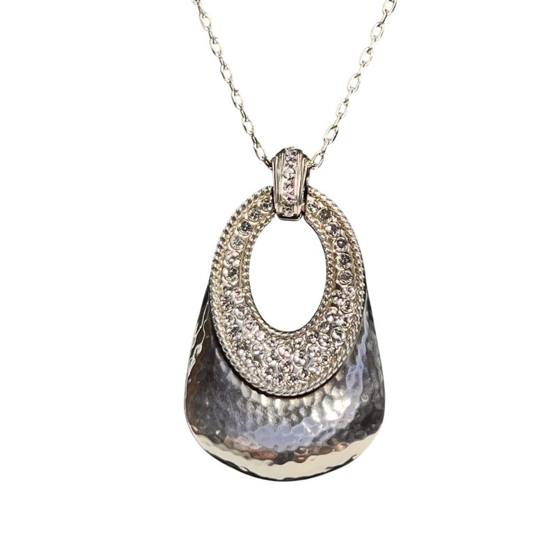 May include: Silver necklace with a hammered-metal pendant. The pendant has an oval top section set with small, clear crystals. The lower part of the pendant has a textured, hammered finish.