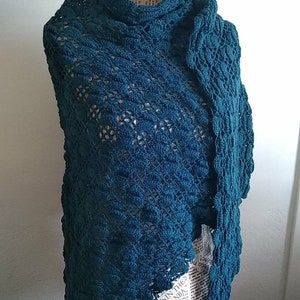 Puede incluir: Chaleco de ganchillo de color turquesa con un patr&oacute;n de encaje. El chal est&aacute; drapeado sobre un maniqu&iacute;.