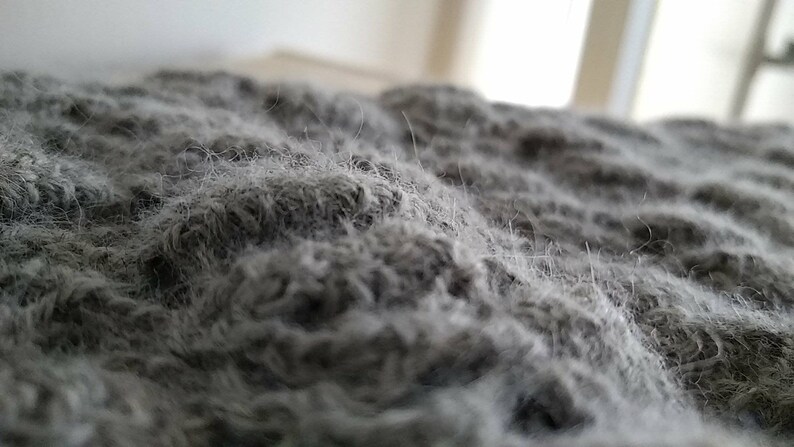 Puede incluir: Primer plano de una tela gris y peluda con una superficie texturizada.