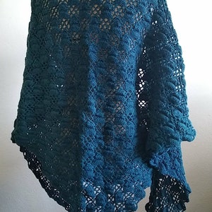 Puede incluir: Chaleco de ganchillo color turquesa con un delicado patr&oacute;n de encaje. El chal est&aacute; drapeado sobre un maniqu&iacute; y tiene un borde con flecos.