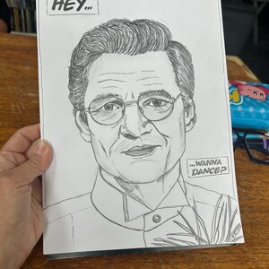 May include: A black and white pencil sketch of a man wearing glasses. The sketch includes the text "HEY..." and "...WANNA DANCE?" in speech bubbles. The drawing is on a white piece of paper.