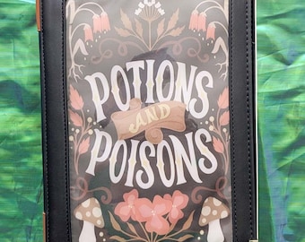 May include: Black faux leather book-style case with gold corner accents. The cover features the words "POTIONS AND POISONS" in white script, surrounded by floral and mushroom illustrations in pink, brown, and green.