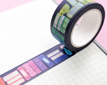 May include: A roll of black washi tape with a colorful pattern of stacked books. The tape is unrolled on a white gridded notebook.