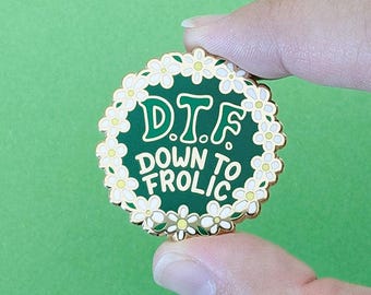 May include: A green enamel pin with a gold border and white daisy accents. The pin reads "D.T.F. Down To Frolic".