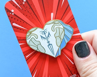 May include: A gold heart-shaped enamel pin with a blue and white design. The pin features a stylized sword and the text "F.O.E." The pin is displayed on a red background with white stars and a white border. The text "kitcronk.com" is printed on the bottom of the card.
