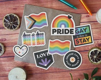 May include: A set of nine rainbow pride stickers with various designs, including a rainbow flag, a heart with stars, a rainbow arch, and the text "love is love".