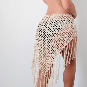 May include: A white crochet skirt with fringe detailing. The skirt is made of a lightweight, airy fabric and has a loose, flowing fit.