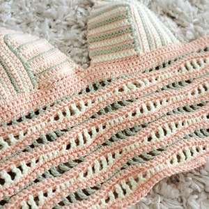 Puede incluir: Un top de crochet con un delicado dise&ntilde;o de tejido abierto en tonos rosa, verde y blanco. El top presenta un escote triangular y una longitud recortada.