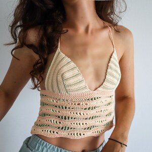 Puede incluir: Un top corto de crochet con escote en V y un patr&oacute;n de rayas rosa y verde.