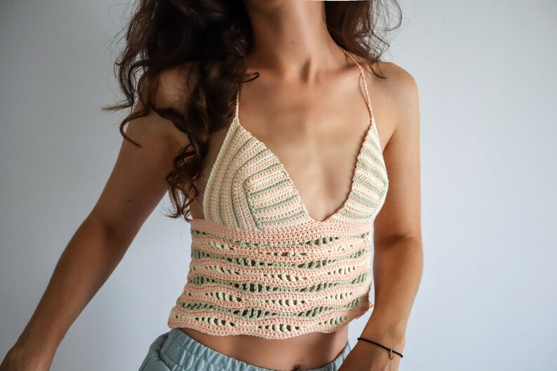 Puede incluir: Un top corto de crochet con escote en V y un patr&oacute;n de rayas rosa y verde.