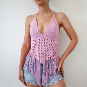 May include: A pink crochet halter top with fringe detailing. The top has a deep V-neckline and is made with a delicate crochet stitch.