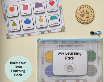 May include: A clear plastic zippered pouch with a white background and a rainbow pattern. The pouch contains a set of colorful learning cards with the text "I can match shapes" and "I can match colors". The pouch also includes a wooden circle with the text "Chloe Leigh Learning".