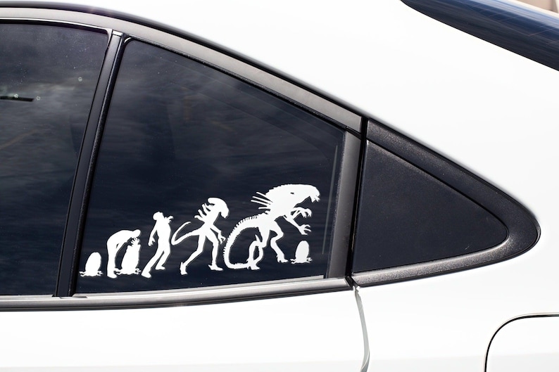 May include: A white vinyl sticker depicting the evolution of the Alien creature from the movie franchise. The sticker shows a progression from a single-celled organism to the iconic Xenomorph.