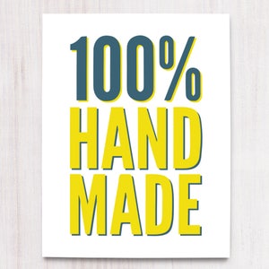 May include: A white print with the words "100% HAND MADE" in large, bold, yellow letters with a dark teal shadow. The text is centered on the print.