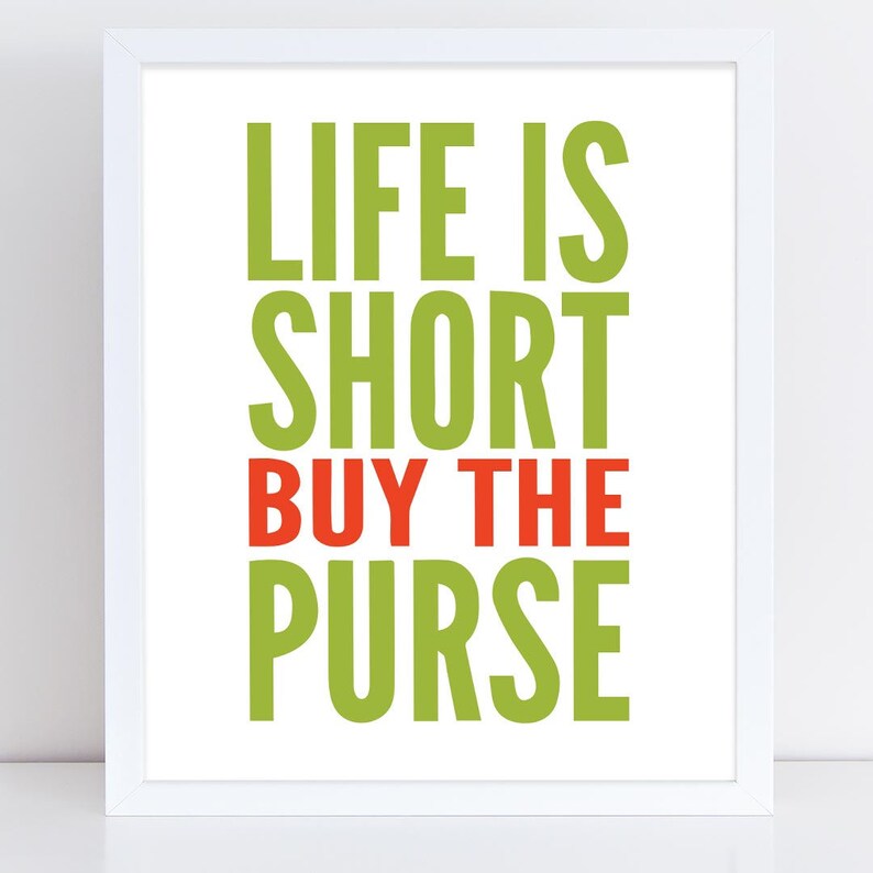 May include: A white framed print with the text "Life is short buy the purse" in green and red letters.