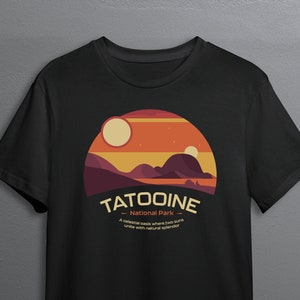 May include: Black t-shirt with a graphic design of a desert landscape with two suns, the text "Tatooine - National Park - A celestial oasis where two suns unite with natural splendor".