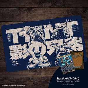 May include: A rectangular dark blue playmat featuring a graphic illustration of the Teenage Mutant Ninja Turtles with the text TMNT and Japanese characters. The mat includes the text EST. 1984 and lists names. A Magic The Gathering card is placed on top.