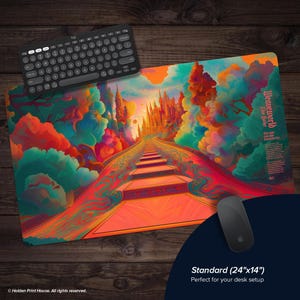 May include: A desk mat with a vibrant fantasy scene, depicting a path leading to a castle. The mat measures 61cm x 36cm. A black keyboard and mouse are placed on a wooden surface next to the mat.