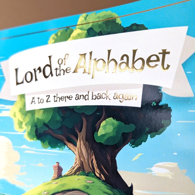 Puede incluir: Portada de libro infantil con el t&iacute;tulo "Lord of the Alphabet" en letras doradas sobre una pancarta blanca. La ilustraci&oacute;n presenta un gran &aacute;rbol, una peque&ntilde;a casa con chimenea y un cielo azul con nubes. Tambi&eacute;n se ve el texto "A to Z there and back again".
